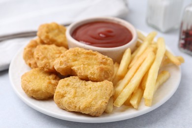 Photo of Tasty chicken nuggets and french fries with sauce on light table, closeup