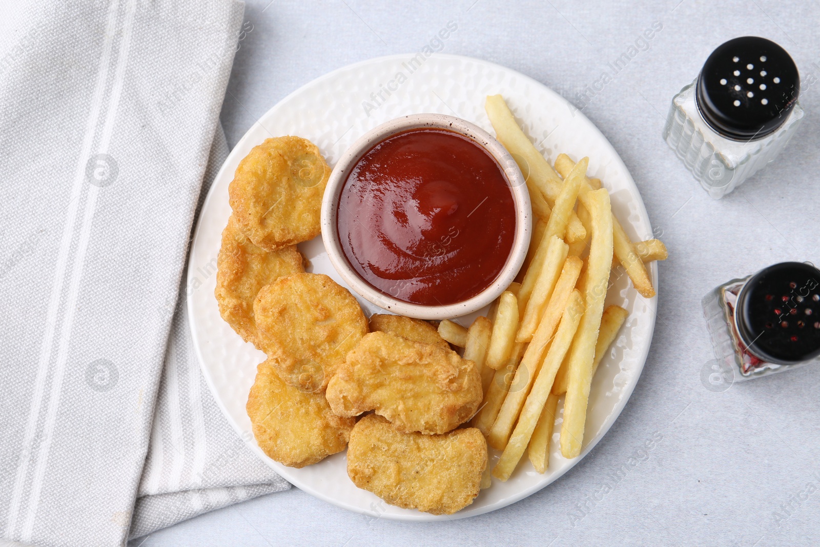 Tasty chicken nuggets and french fries with sauce on light table, flat lay Photo of Tasty chicken nuggets and french fries with sauce on light table, flat lay