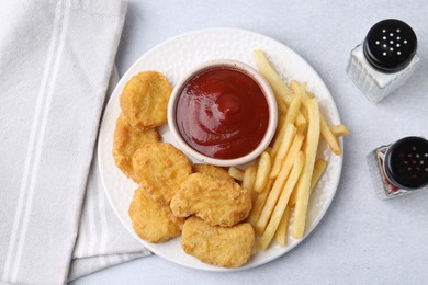 Photo of Tasty chicken nuggets and french fries with sauce on light table, flat lay