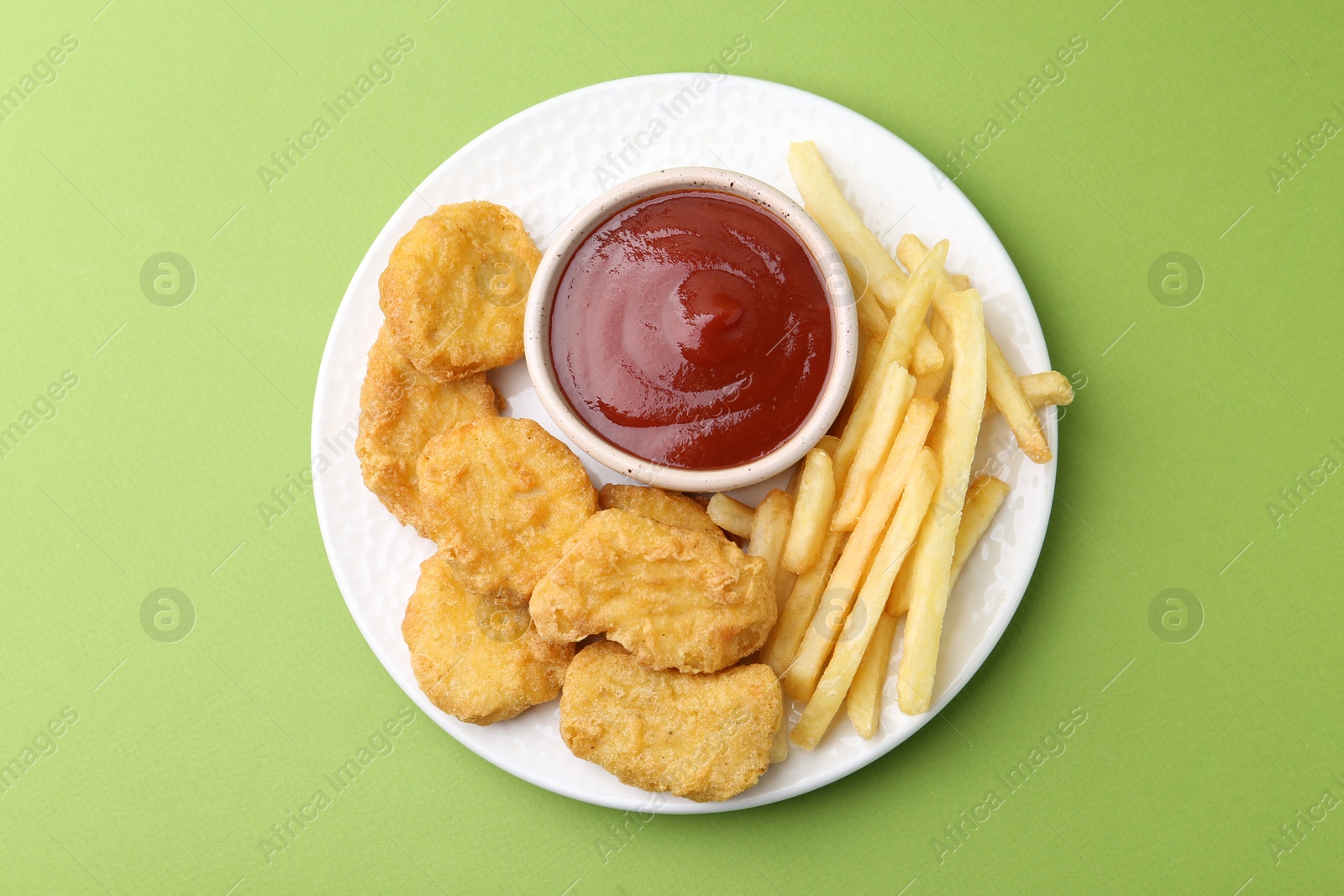 Tasty chicken nuggets and french fries with sauce on green background, top view Photo of Tasty chicken nuggets and french fries with sauce on green background, top view