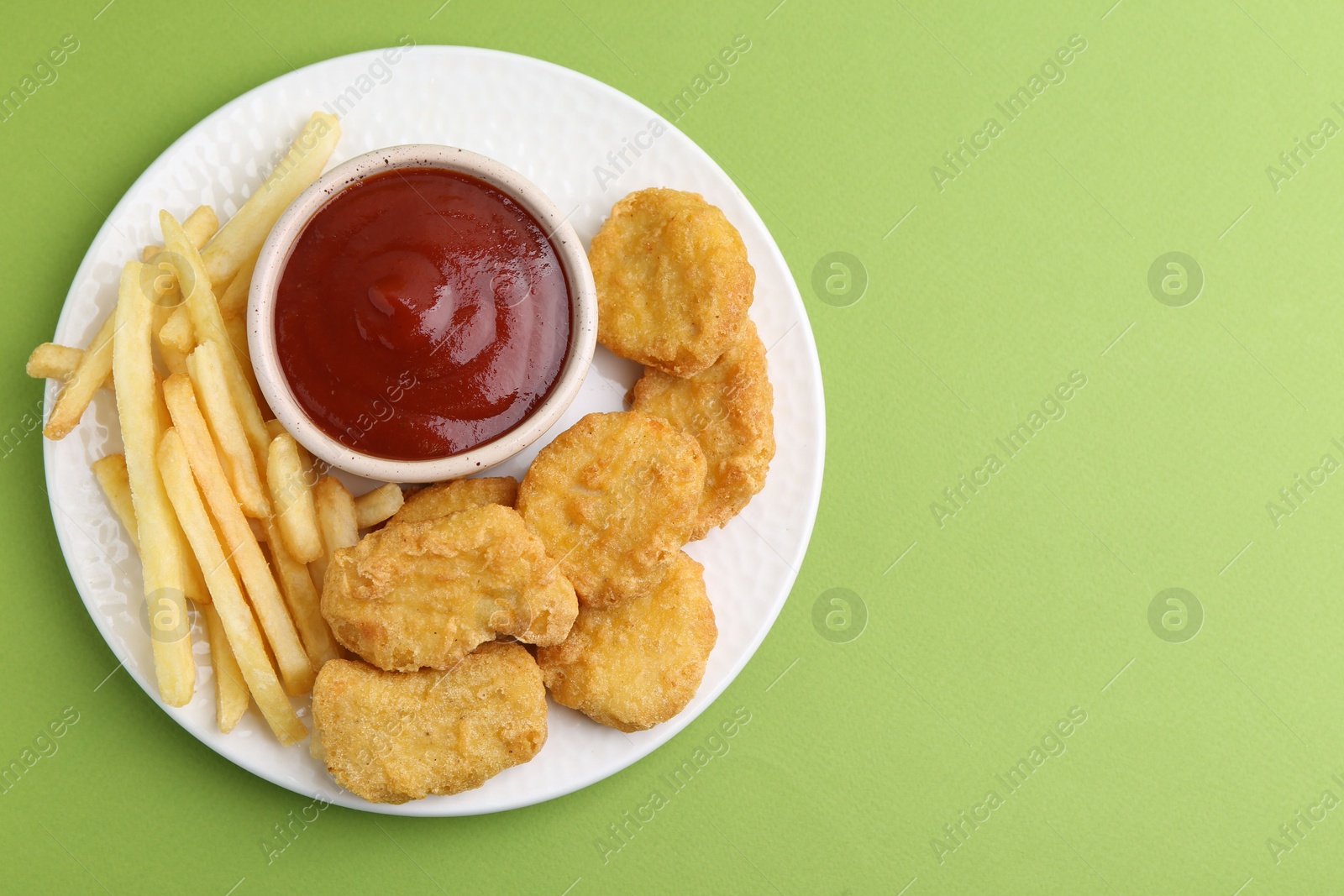 Tasty chicken nuggets and french fries with sauce on green background, top view. Space for text Photo of Tasty chicken nuggets and french fries with sauce on green background, top view. Space for text