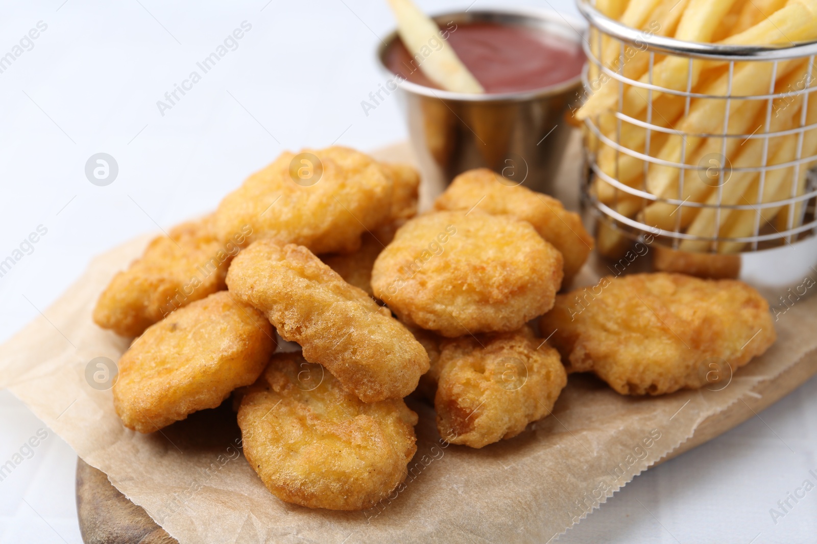 Tasty chicken nuggets, potato fries and ketchup on white tiled table, closeup Photo of Tasty chicken nuggets, potato fries and ketchup on white tiled table, closeup