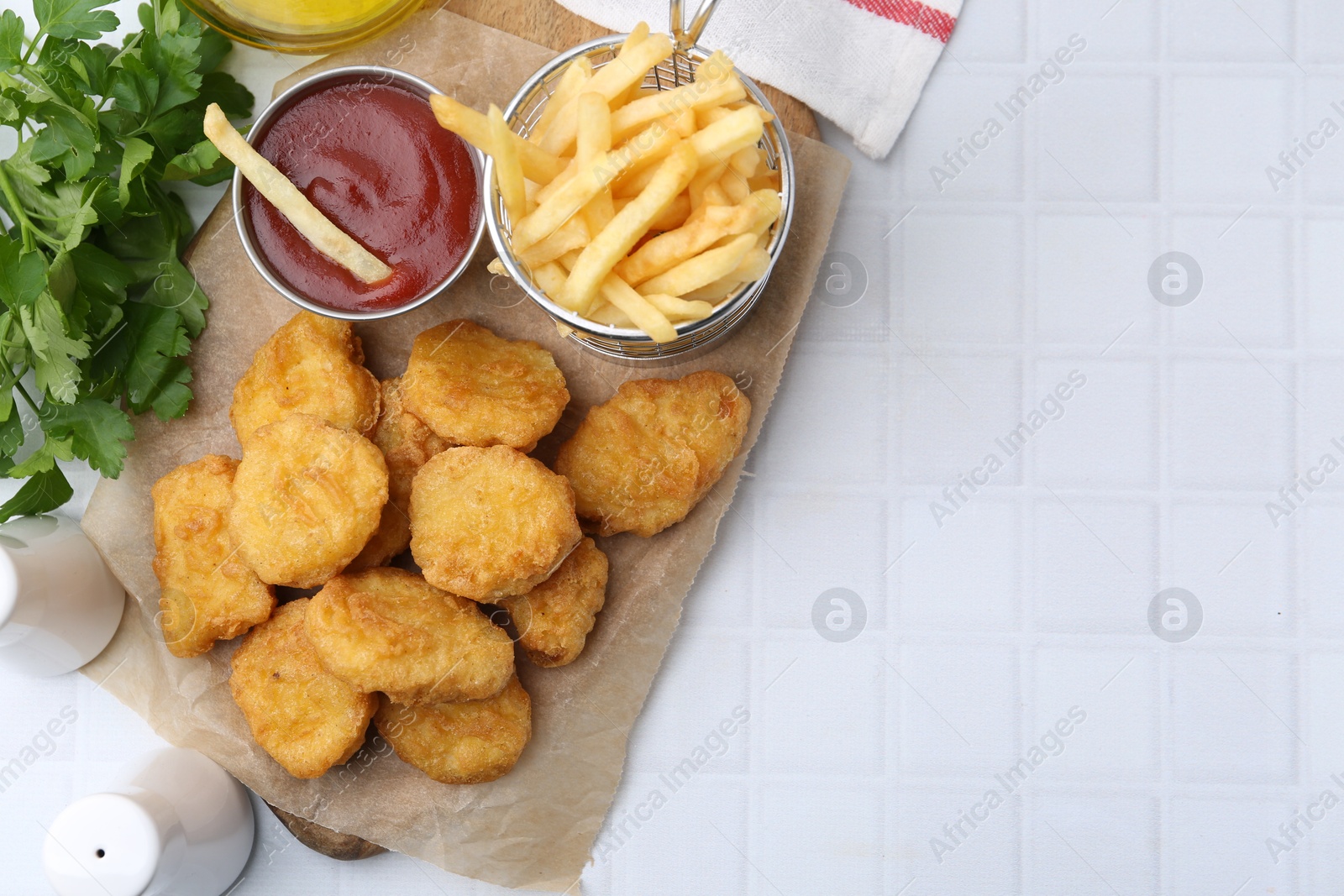 Tasty chicken nuggets, potato fries and ketchup on white tiled table, flat lay. Space for text Photo of Tasty chicken nuggets, potato fries and ketchup on white tiled table, flat lay. Space for text