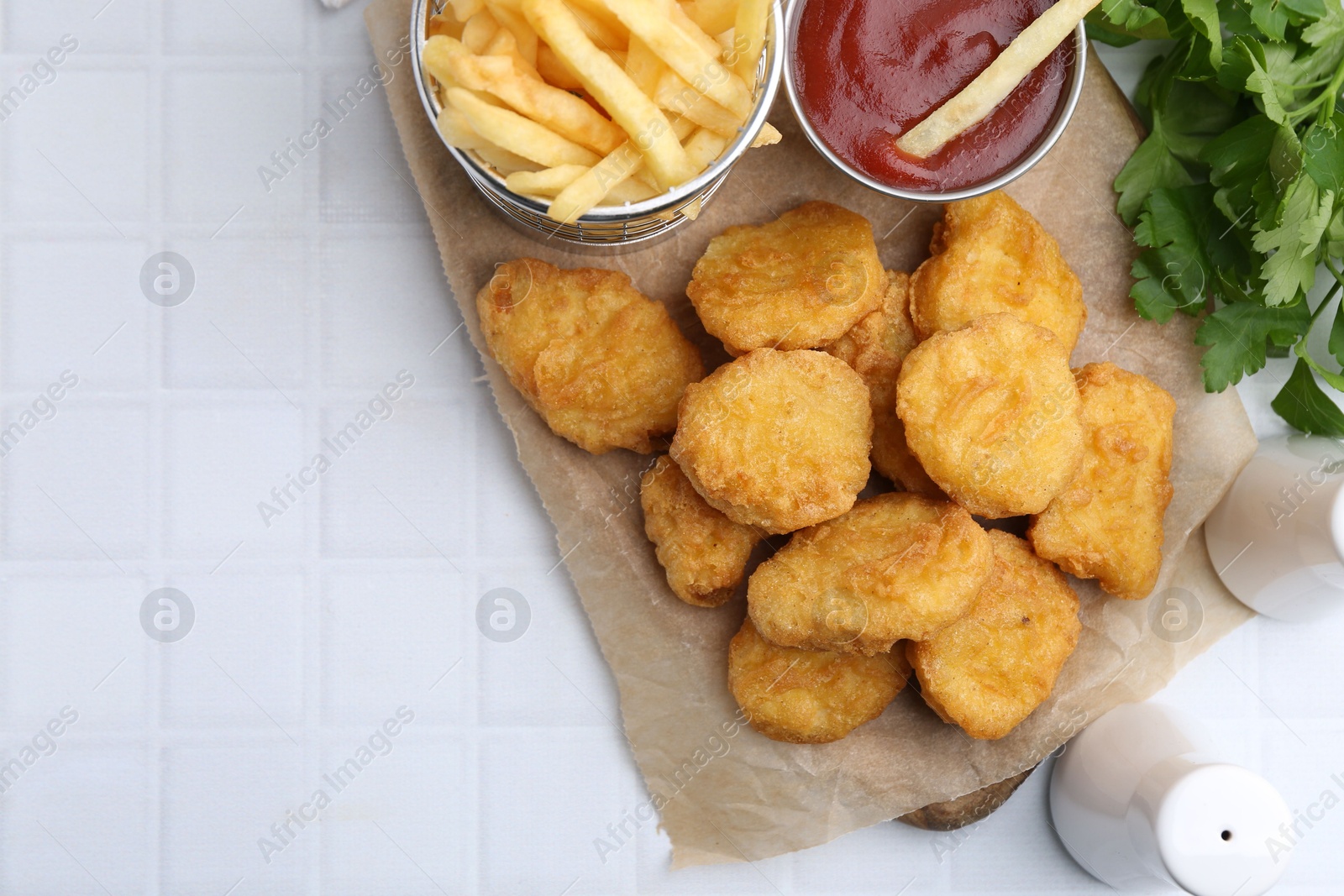 Tasty chicken nuggets, potato fries and ketchup on white tiled table, flat lay. Space for text Photo of Tasty chicken nuggets, potato fries and ketchup on white tiled table, flat lay. Space for text
