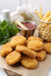 Photo of Tasty chicken nuggets, potato fries and ketchup on white table, closeup