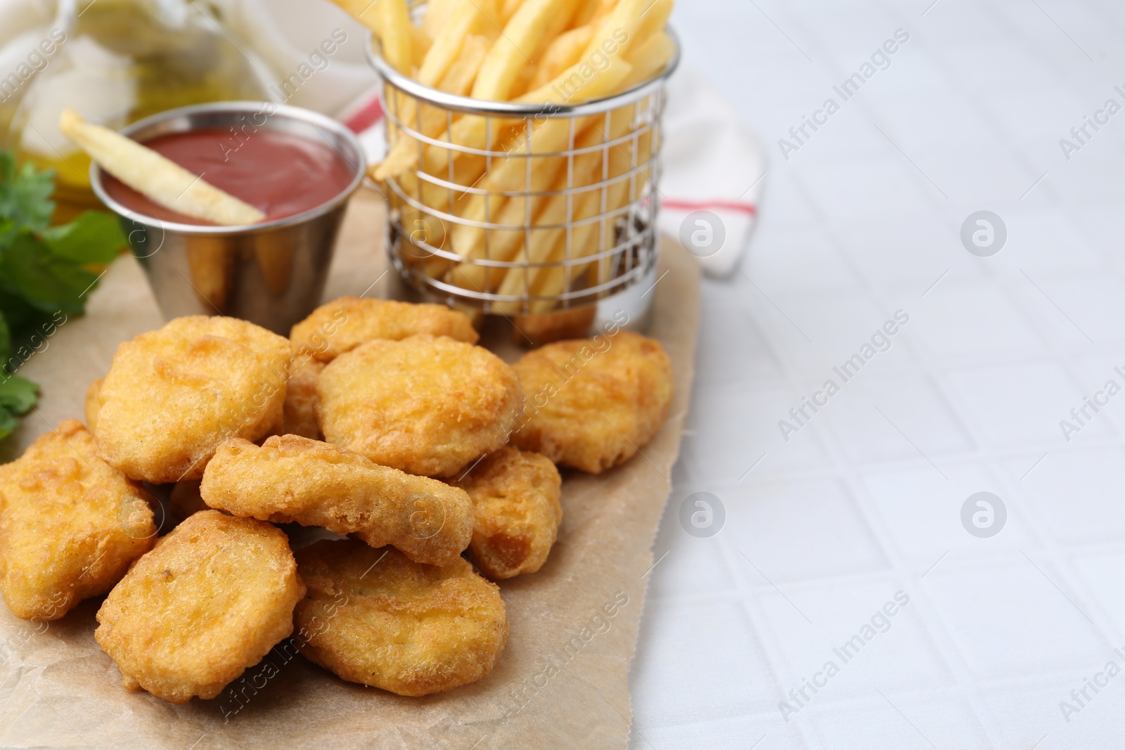 Tasty chicken nuggets, potato fries and ketchup on white tiled table, closeup. Space for text Photo of Tasty chicken nuggets, potato fries and ketchup on white tiled table, closeup. Space for text
