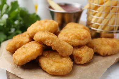 Photo of Tasty chicken nuggets, potato fries and ketchup on white table, closeup