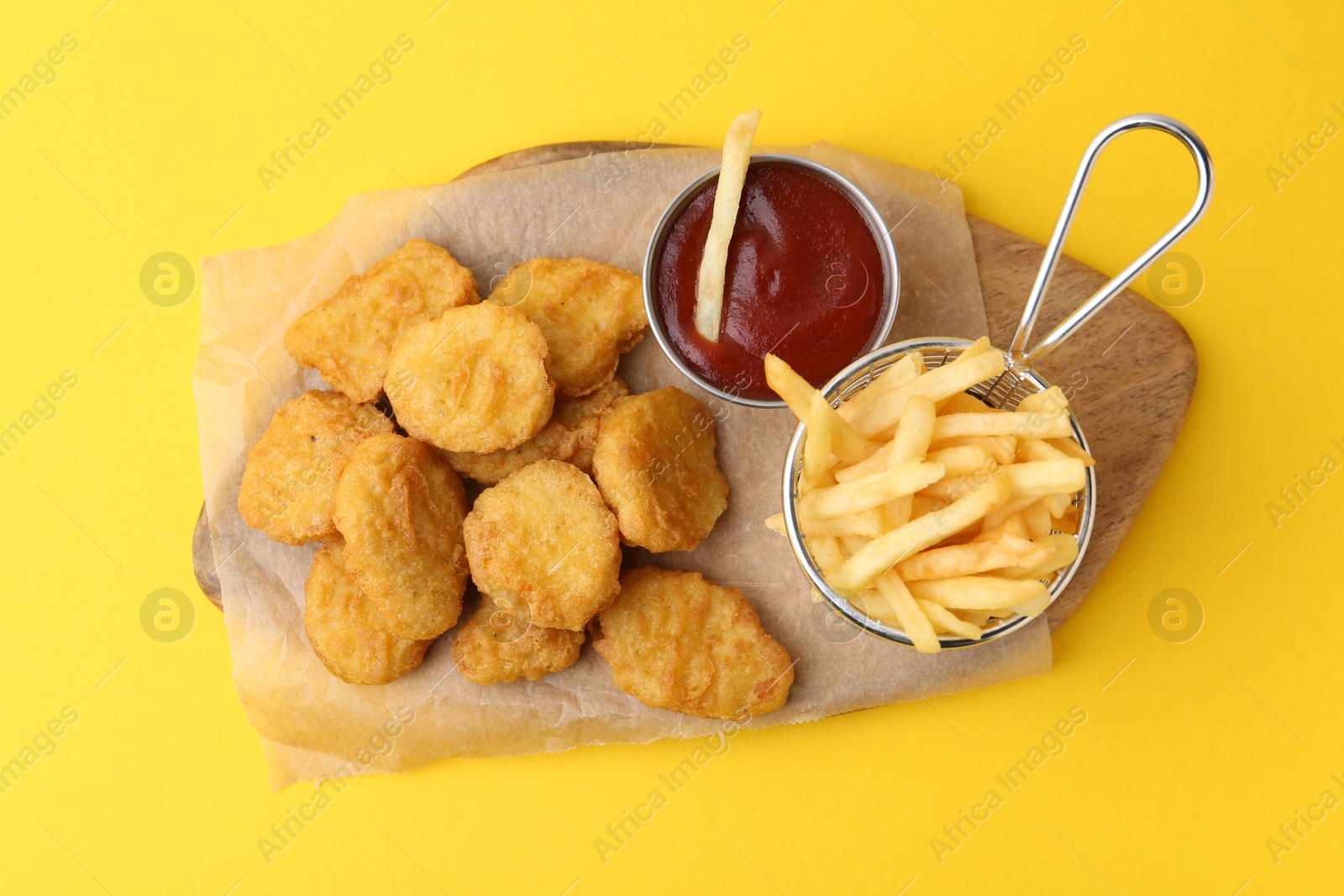 Tasty chicken nuggets, potato fries and sauce on yellow background, top view Photo of Tasty chicken nuggets, potato fries and sauce on yellow background, top view