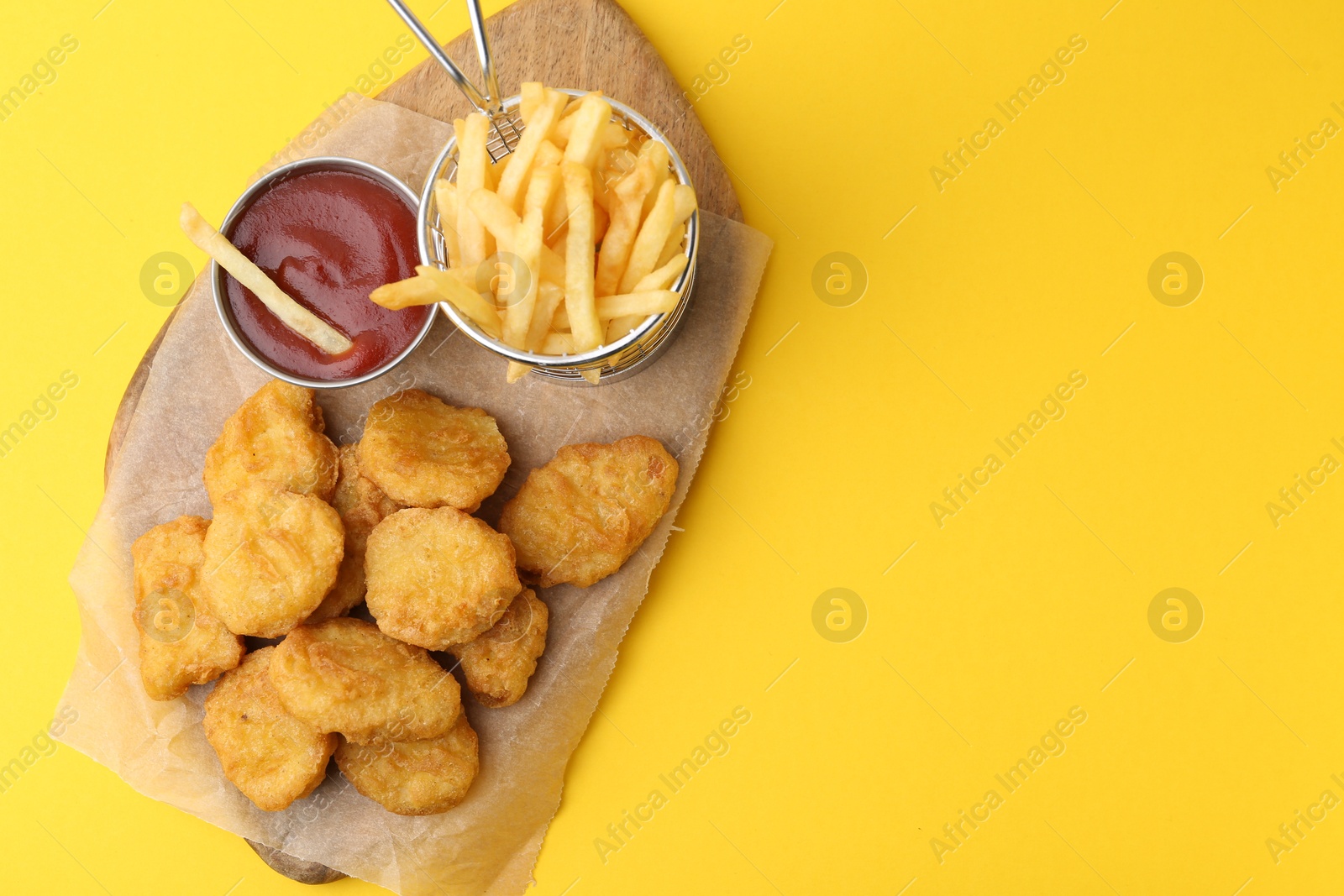 Tasty chicken nuggets, potato fries and sauce on yellow background, top view. Space for text Photo of Tasty chicken nuggets, potato fries and sauce on yellow background, top view. Space for text