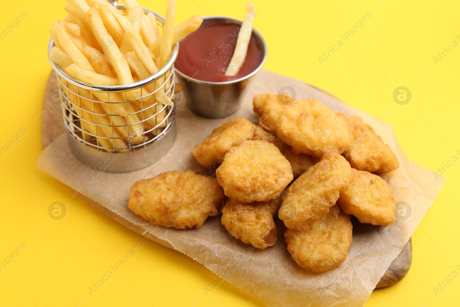 Tasty chicken nuggets, potato fries and sauce on yellow background, closeup Photo of Tasty chicken nuggets, potato fries and sauce on yellow background, closeup