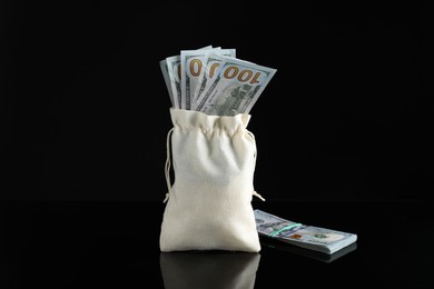 Photo of Burlap sack with dollar banknotes on dark mirror surface