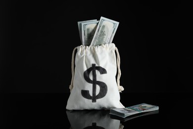 Photo of Burlap sack with dollar banknotes on dark mirror surface