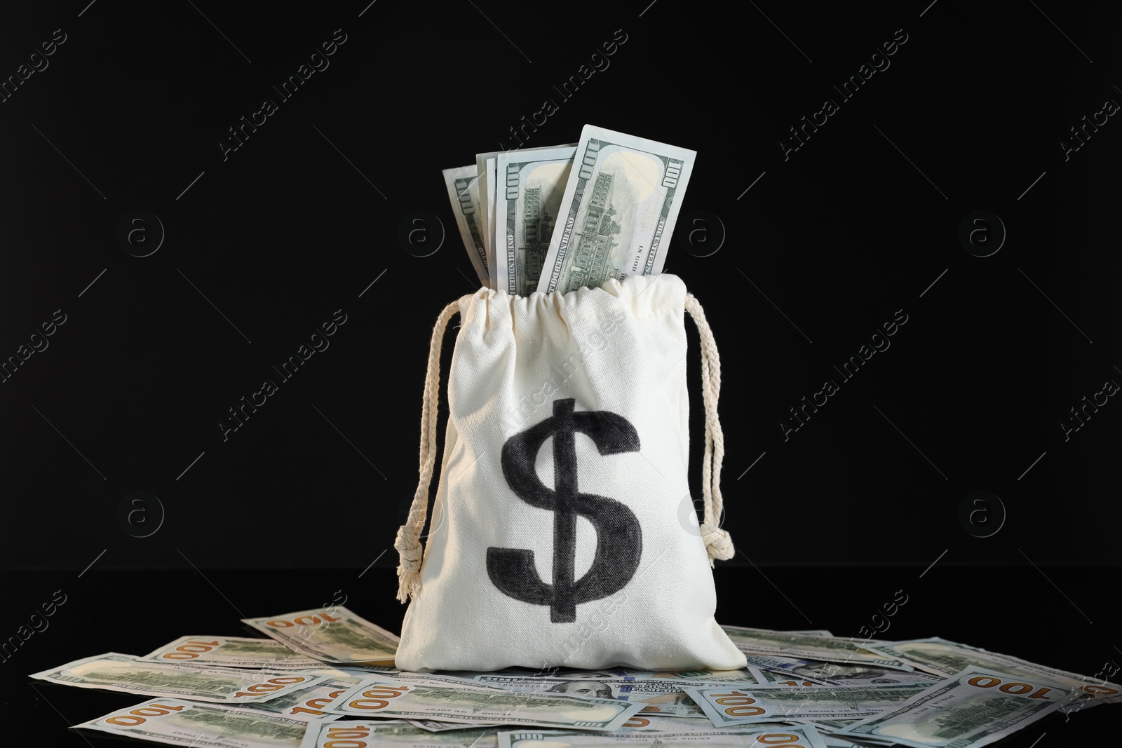 Photo of Burlap sack with dollar banknotes on black background