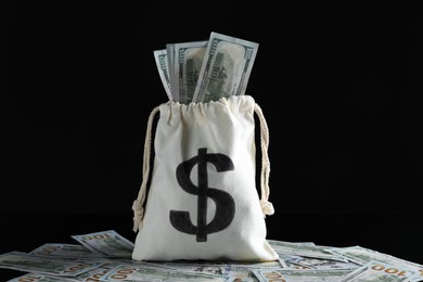 Photo of Burlap sack with dollar banknotes on black background