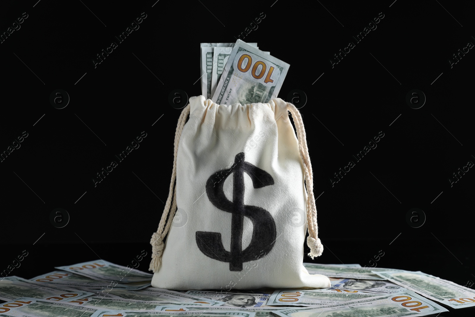 Photo of Burlap sack with dollar banknotes on black background