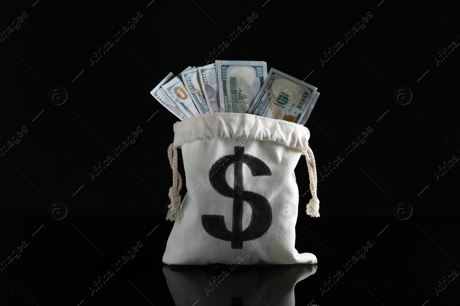 Photo of Dollar banknotes in burlap sack on dark mirror surface