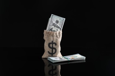 Photo of Burlap sack with dollar banknotes on dark mirror surface