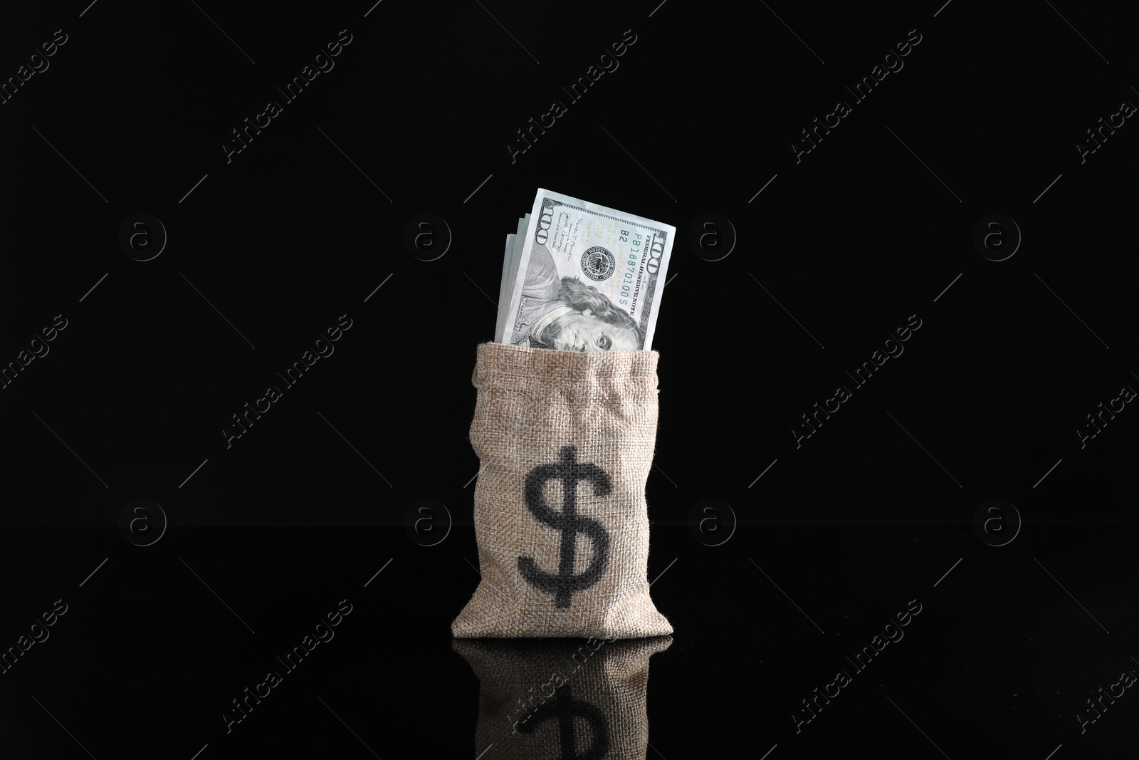 Photo of Dollar banknotes in burlap sack on dark mirror surface