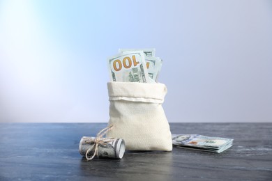 Photo of Burlap sack with dollar banknotes on grey table