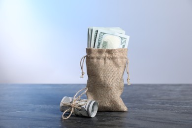 Photo of Burlap sack with dollar banknotes on grey table