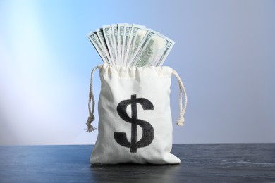 Photo of Dollar banknotes in burlap sack on grey table