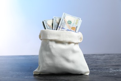 Photo of Dollar banknotes in burlap sack on grey table