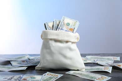 Photo of Burlap sack with dollar banknotes on grey table