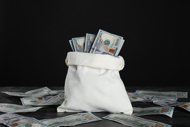 Photo of Burlap sack with dollar banknotes on grey table