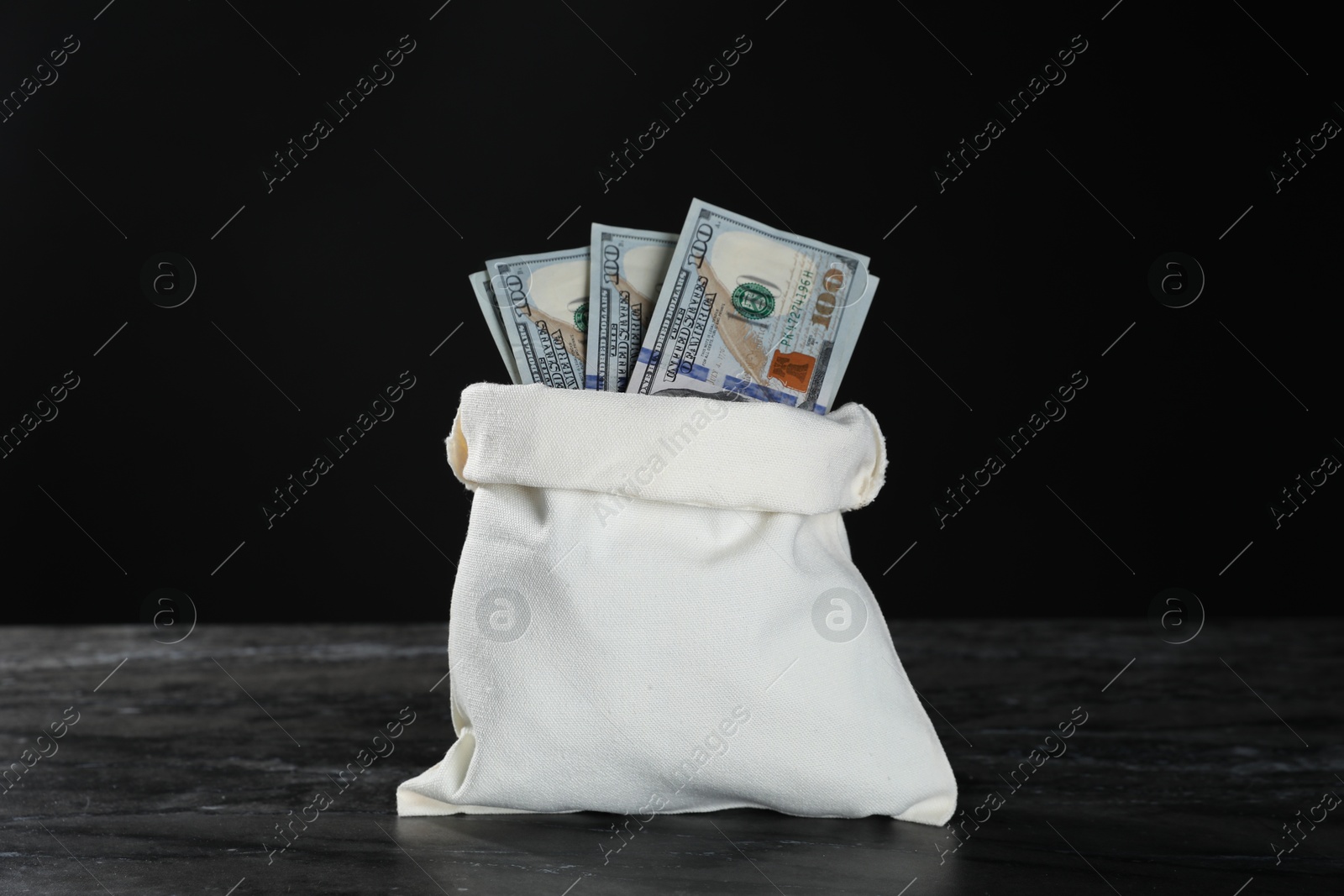 Photo of Dollar banknotes in burlap sack on grey table