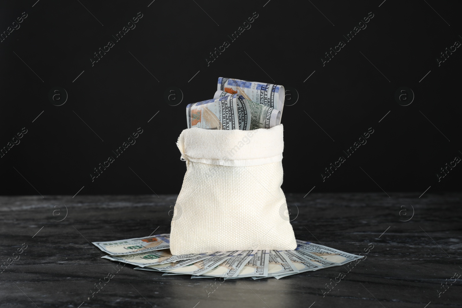 Photo of Burlap sack with dollar banknotes on grey table