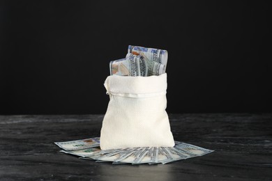 Photo of Burlap sack with dollar banknotes on grey table