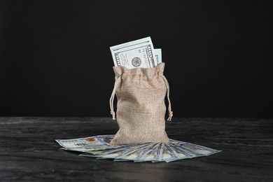 Photo of Burlap sack with dollar banknotes on grey table