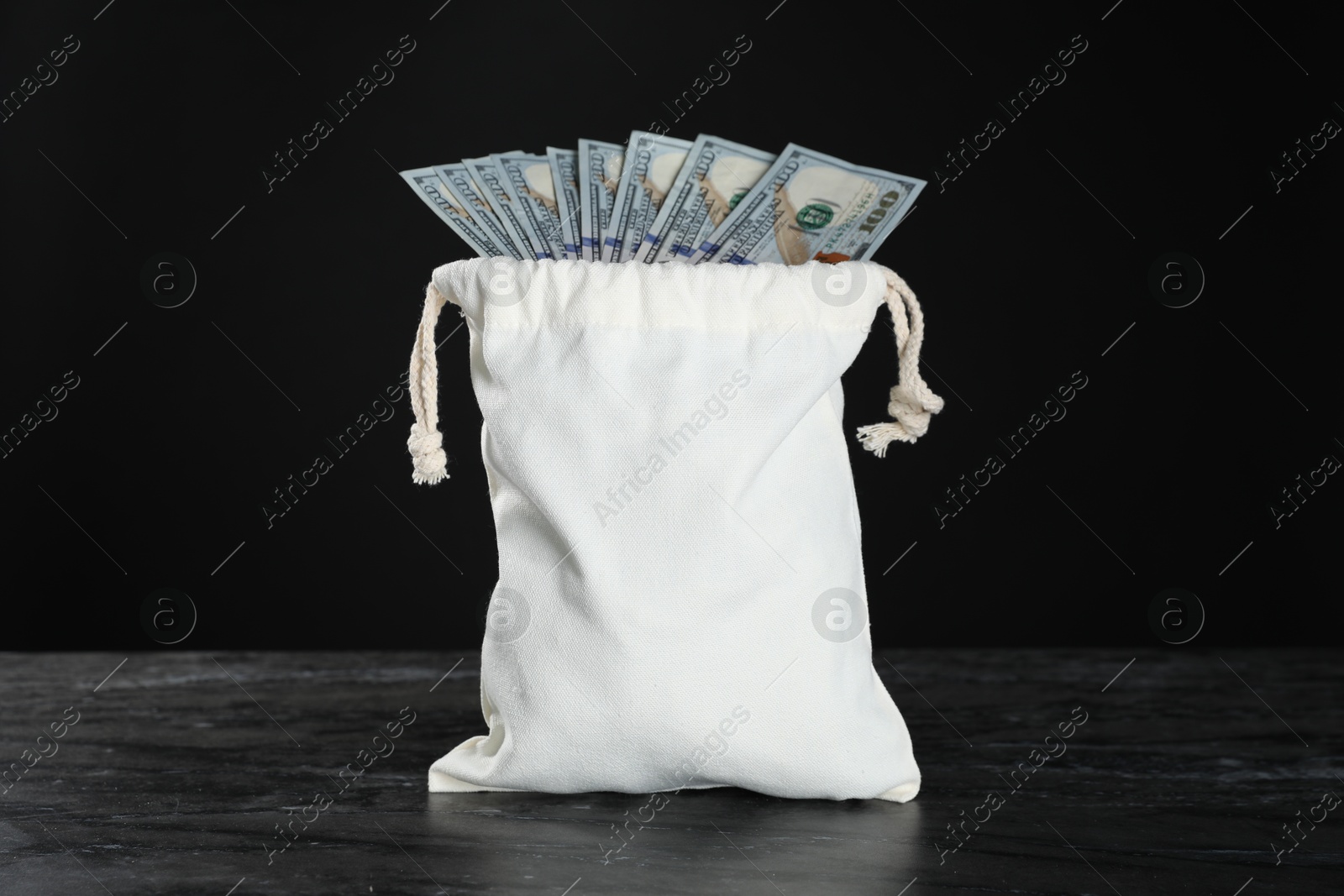 Photo of Dollar banknotes in burlap sack on grey table