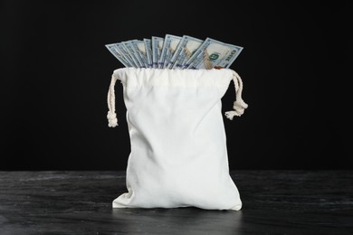 Photo of Dollar banknotes in burlap sack on grey table