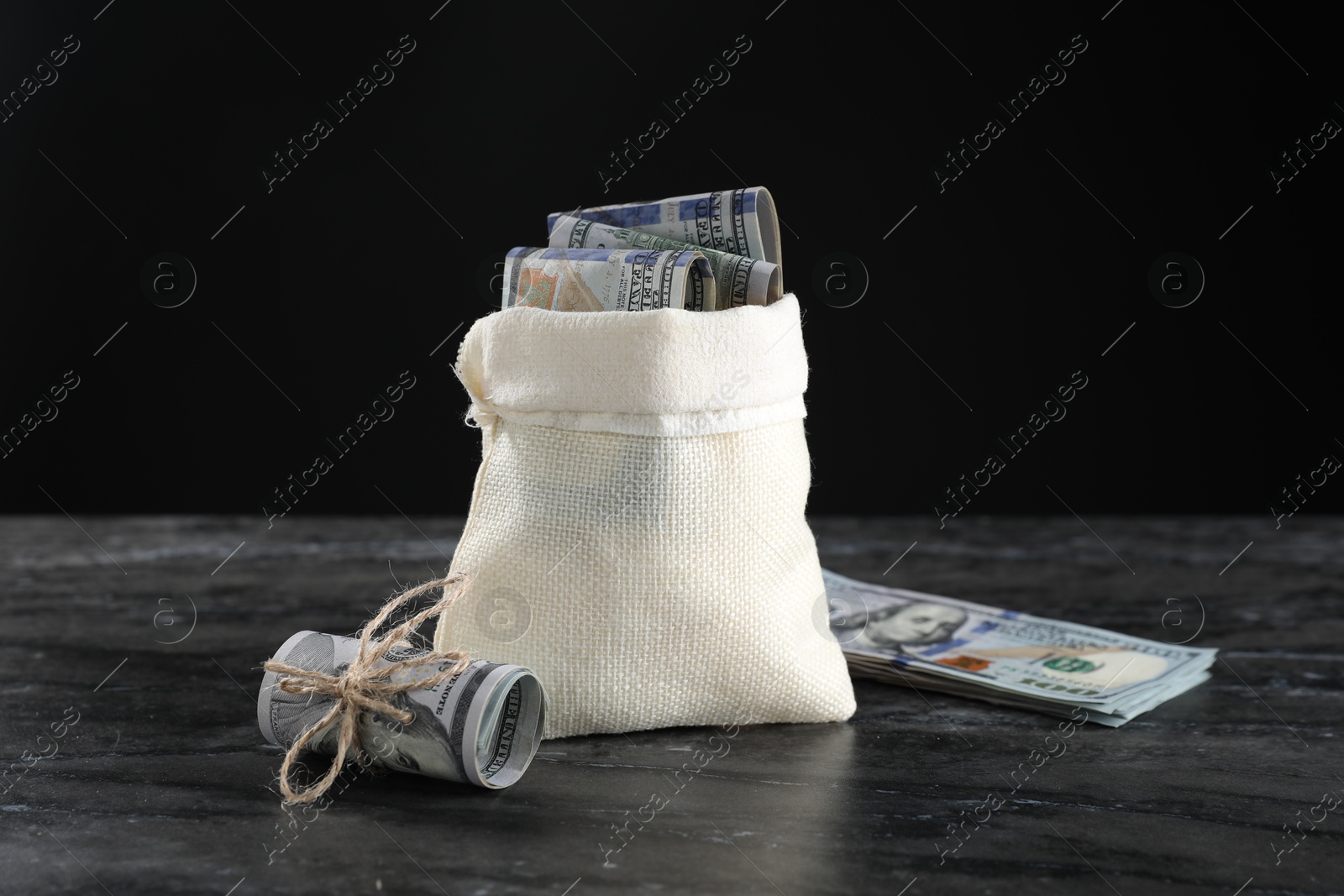 Photo of Burlap sack with dollar banknotes on grey table