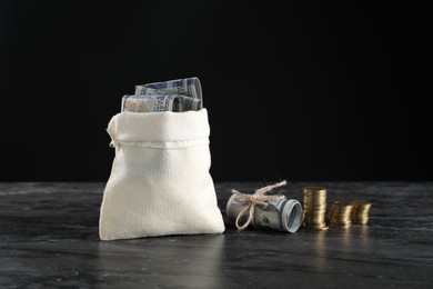 Photo of Burlap sack with dollar banknotes and stacked coins on grey table