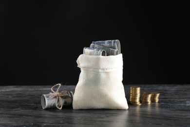 Photo of Burlap sack with dollar banknotes and stacked coins on grey table