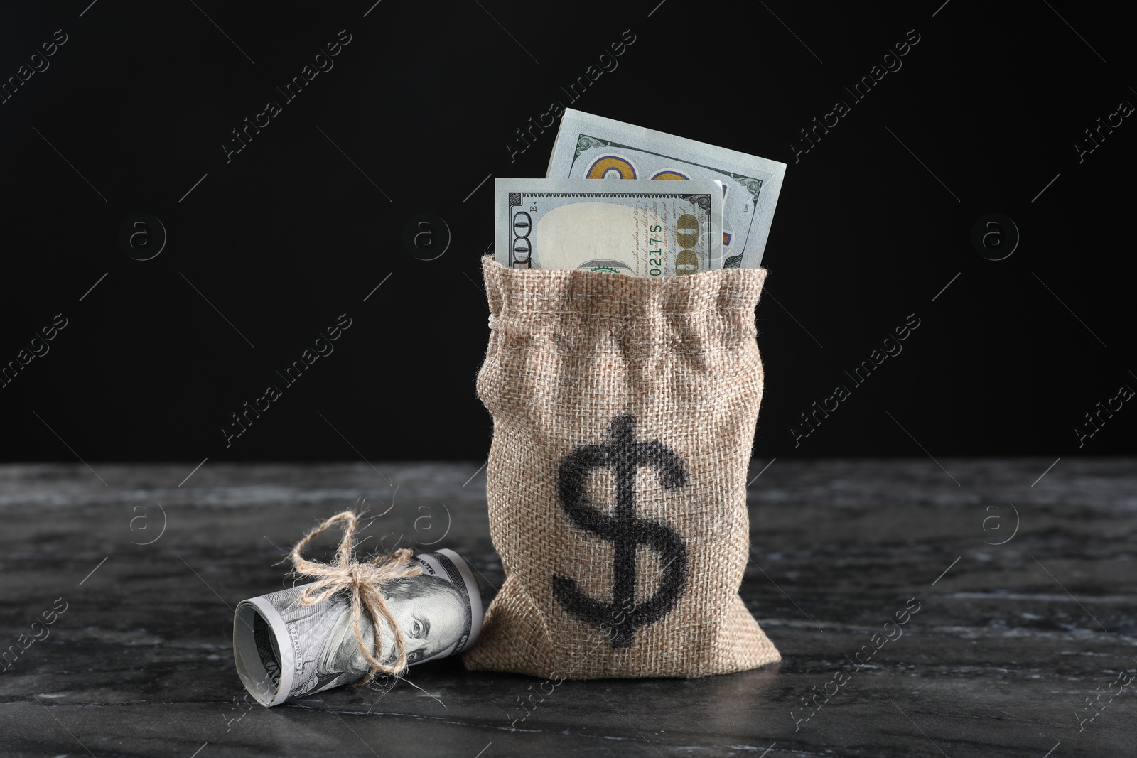 Photo of Burlap sack with dollar banknotes on grey table