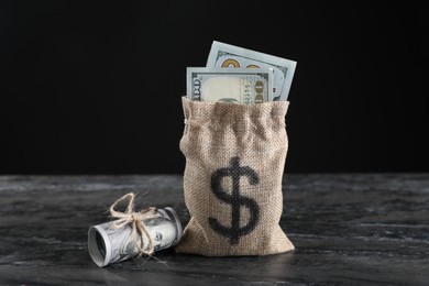 Photo of Burlap sack with dollar banknotes on grey table