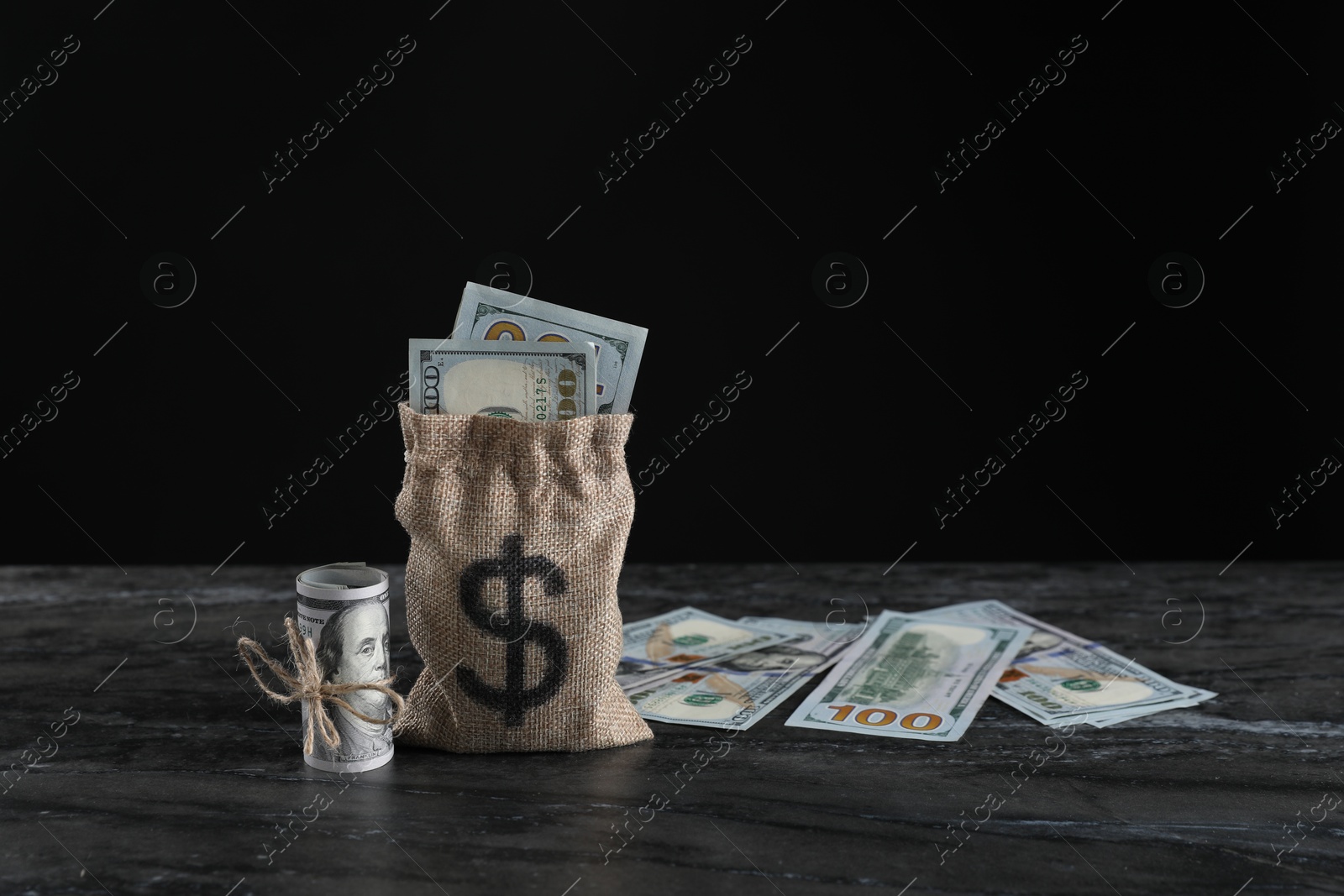 Photo of Burlap sack with dollar banknotes on grey table