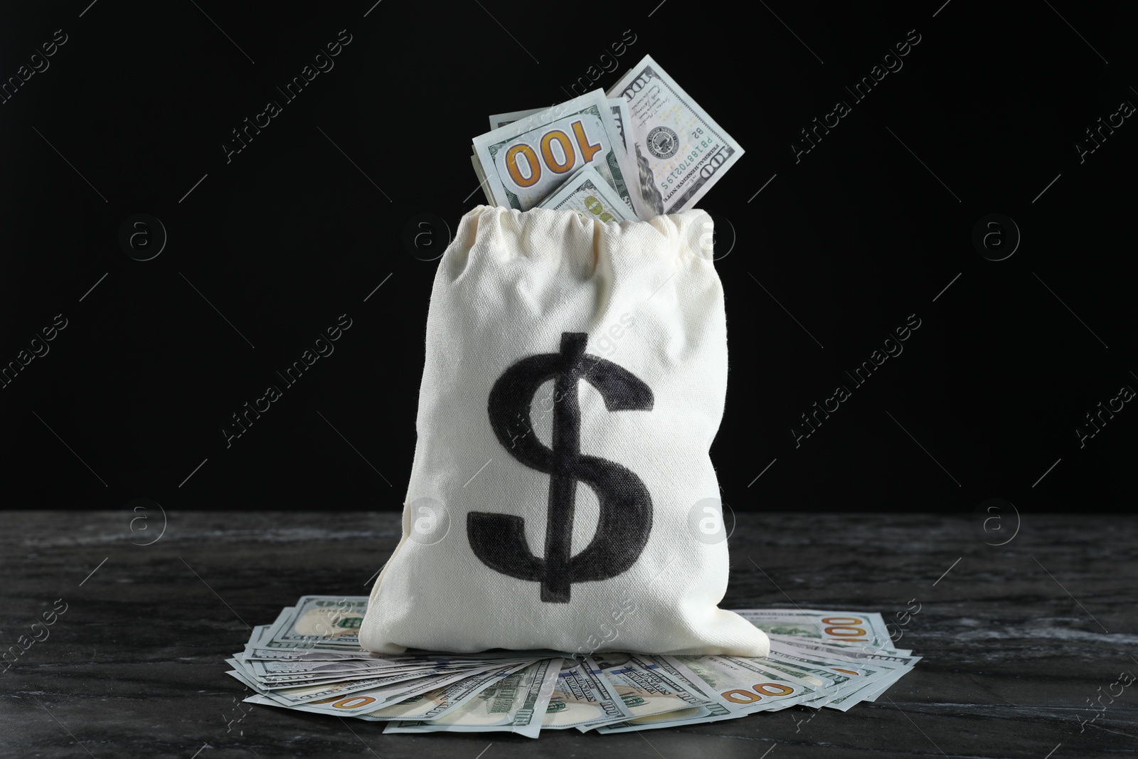 Photo of Burlap sack with dollar banknotes on grey table