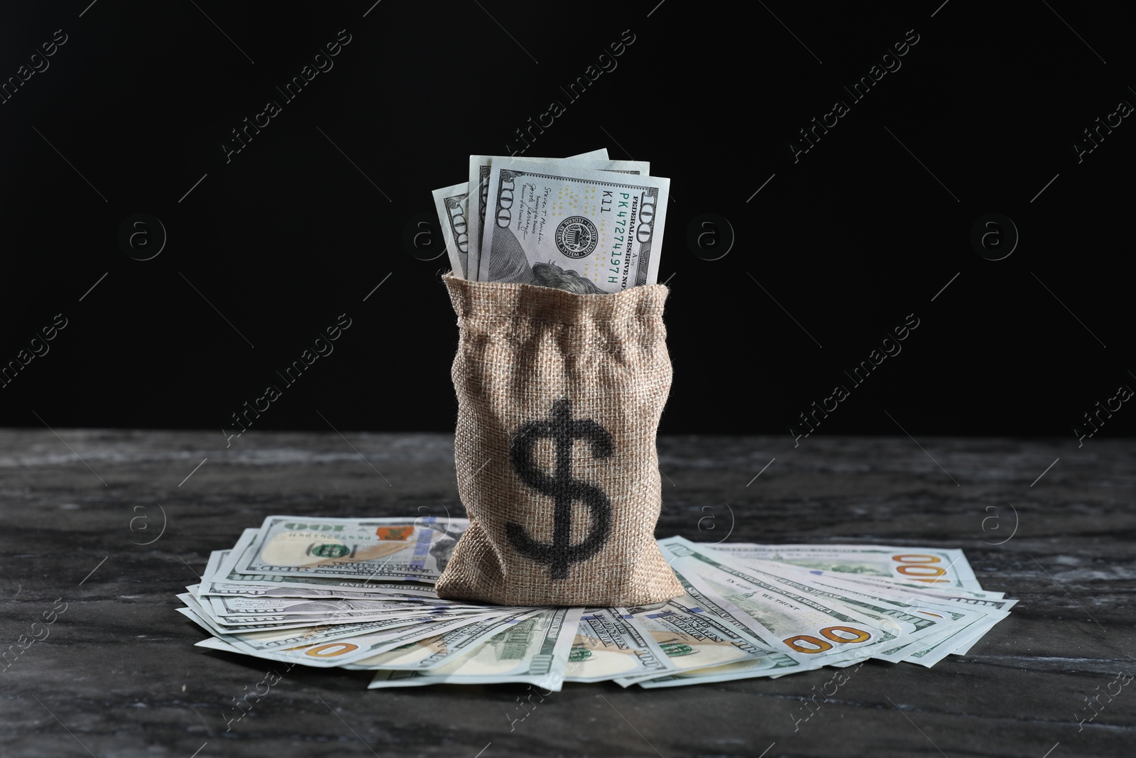 Photo of Burlap sack with dollar banknotes on grey table