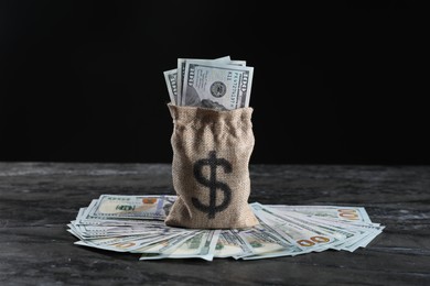 Photo of Burlap sack with dollar banknotes on grey table