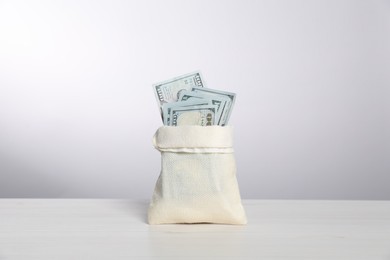 Photo of Dollar banknotes in burlap sack on white table