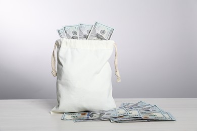 Photo of Burlap sack with dollar banknotes on white table