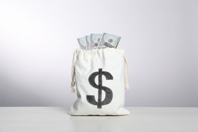 Photo of Dollar banknotes in burlap sack on white table