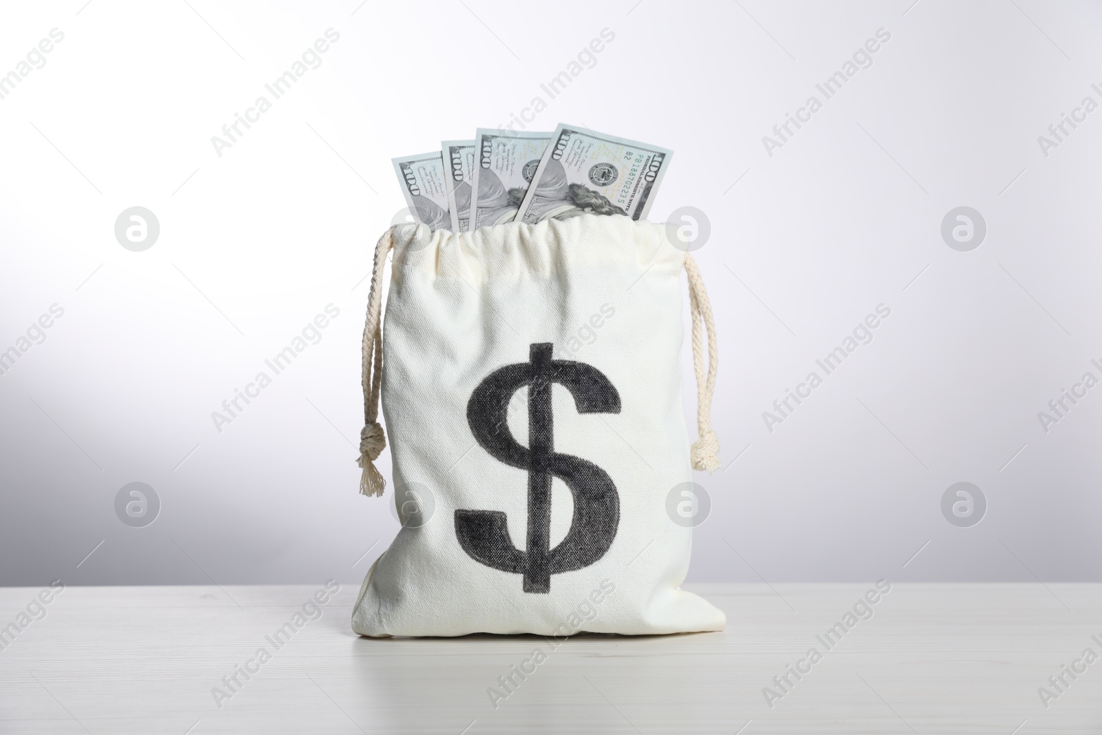 Photo of Dollar banknotes in burlap sack on white table