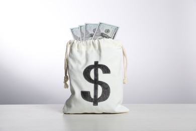 Photo of Dollar banknotes in burlap sack on white table