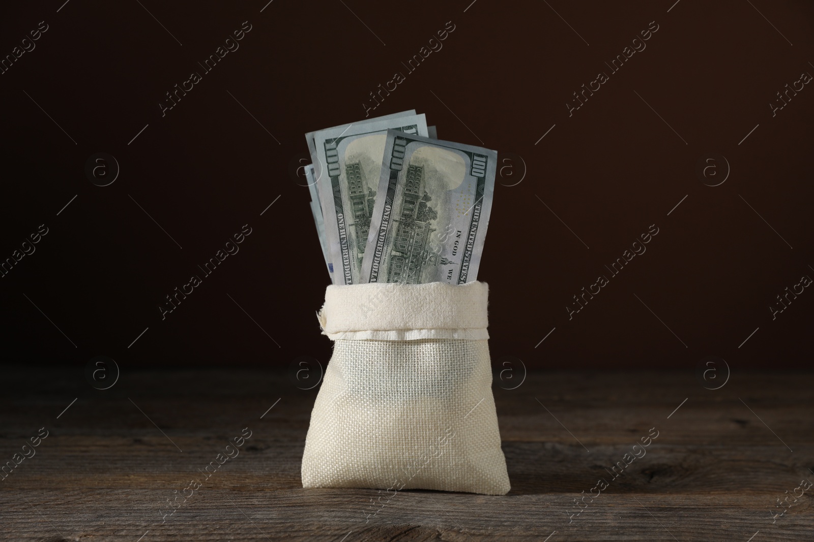 Photo of Dollar banknotes in burlap sack on wooden table