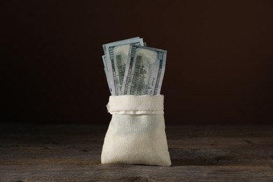 Photo of Dollar banknotes in burlap sack on wooden table